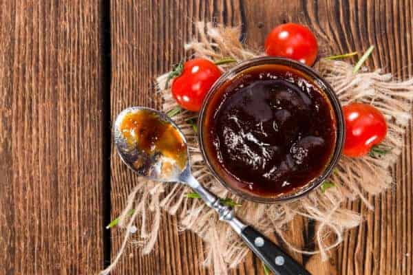 bowl of barbecue sauce with cherry tomatoes on table