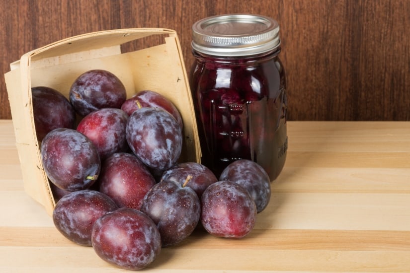 jar of plums and basket of fresh plums on the table