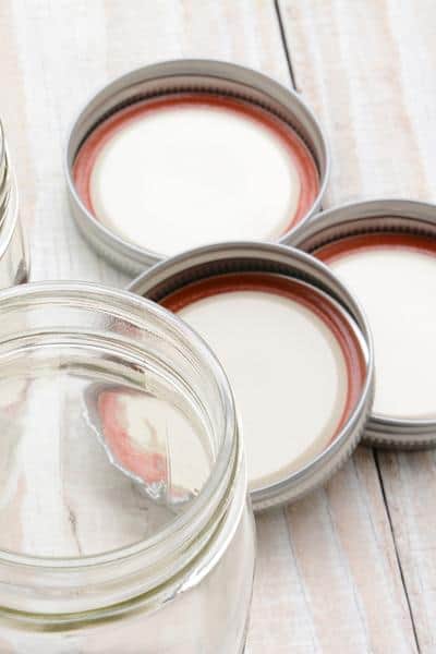 close up of 3 canning lids and bands on a table with a mason jar