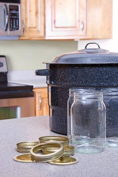 black canning pot with quart jars and lids on a counter