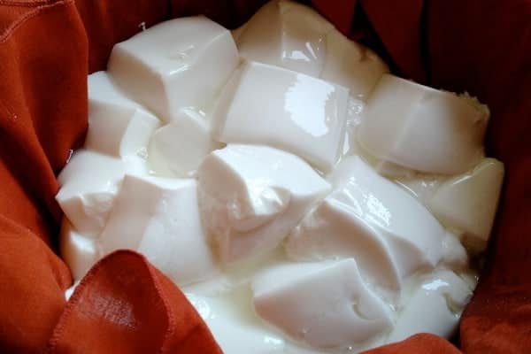 bowl of mozzarella cheese curds draining in a lined colander