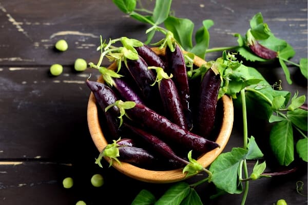 a bowl of purple pea pods on a table