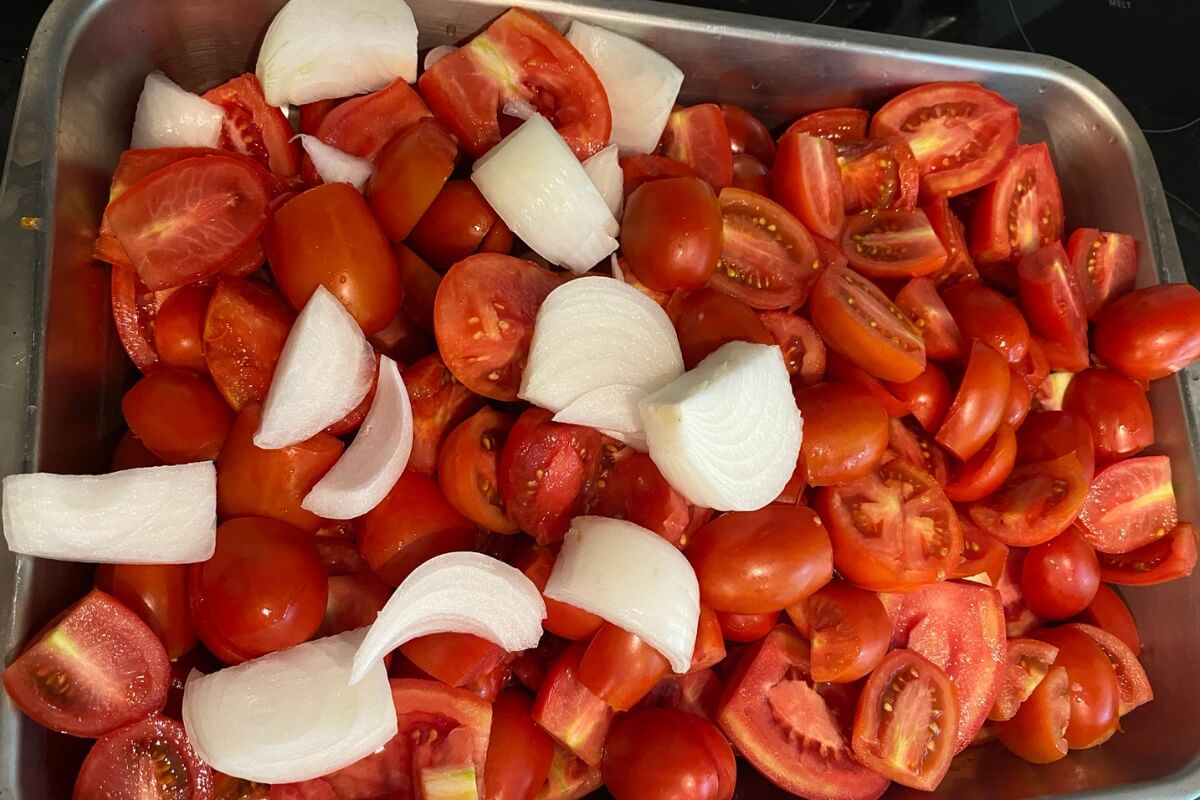 cut tomatoes and onion in roasting pan for tomato sauce