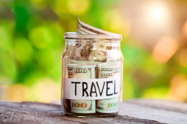 jar of money labeled travel on a table