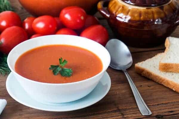 tomato soup in white bowl on a table with spoon