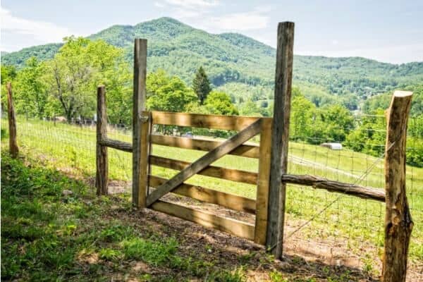 wooden fence gate with a green pasture and mountain behind it