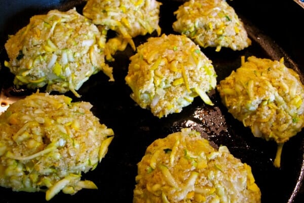 zucchini crab cakes frying in a cast iron skillet