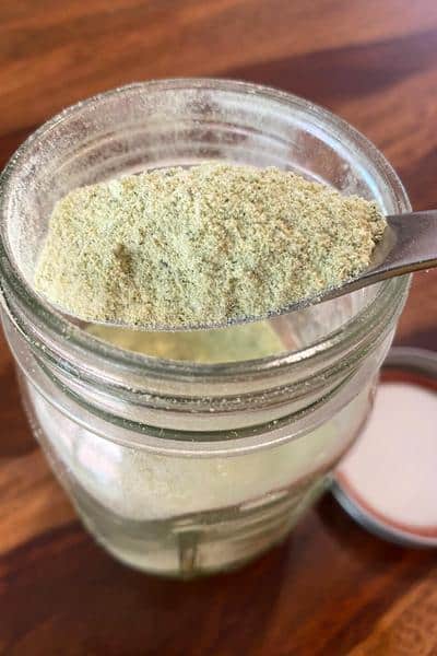 jar of powdered zucchini with a spoonful of the zucchini flour close up